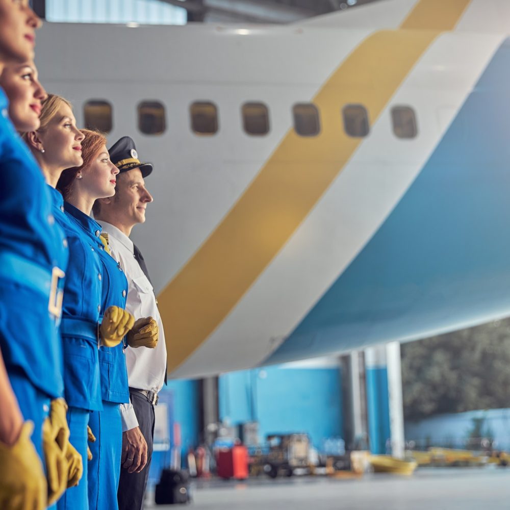 happy-smiling-pilot-and-charming-stewardesses-looking-ahead-in-the-hangar-at-the-airport.jpg